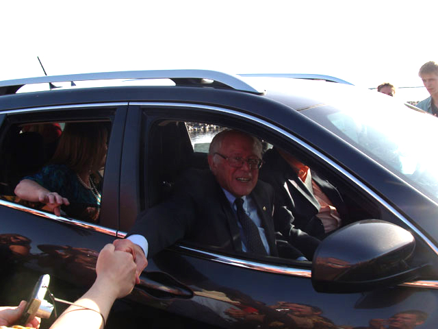 Bernie Sanders shakes the hands of supporters as he leaves the rally in his Jeep