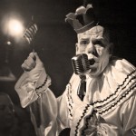 A clown leading the crowd in a rendition of the national anthem.
